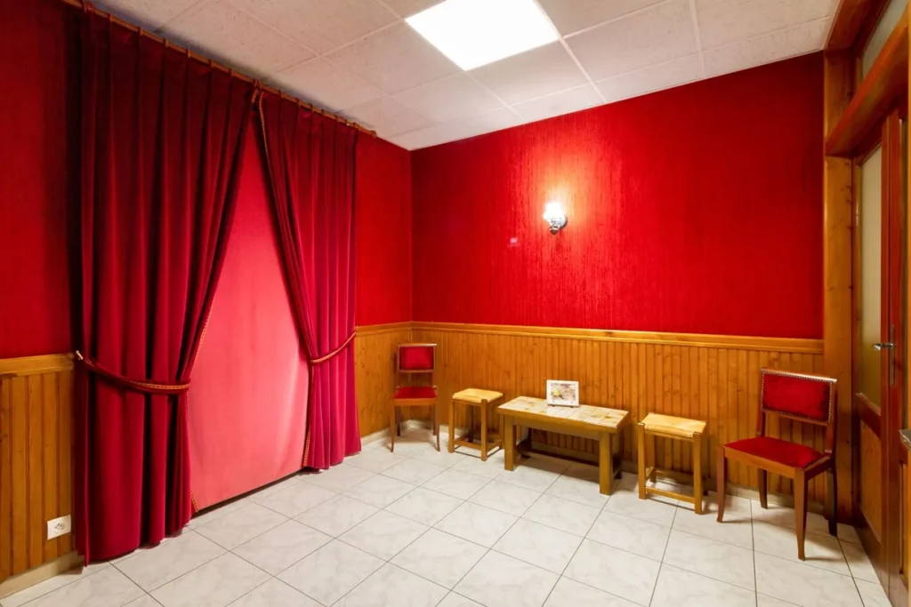 Salon de recueillement funéraire, tentures en velours et chaises en bois pour les familles