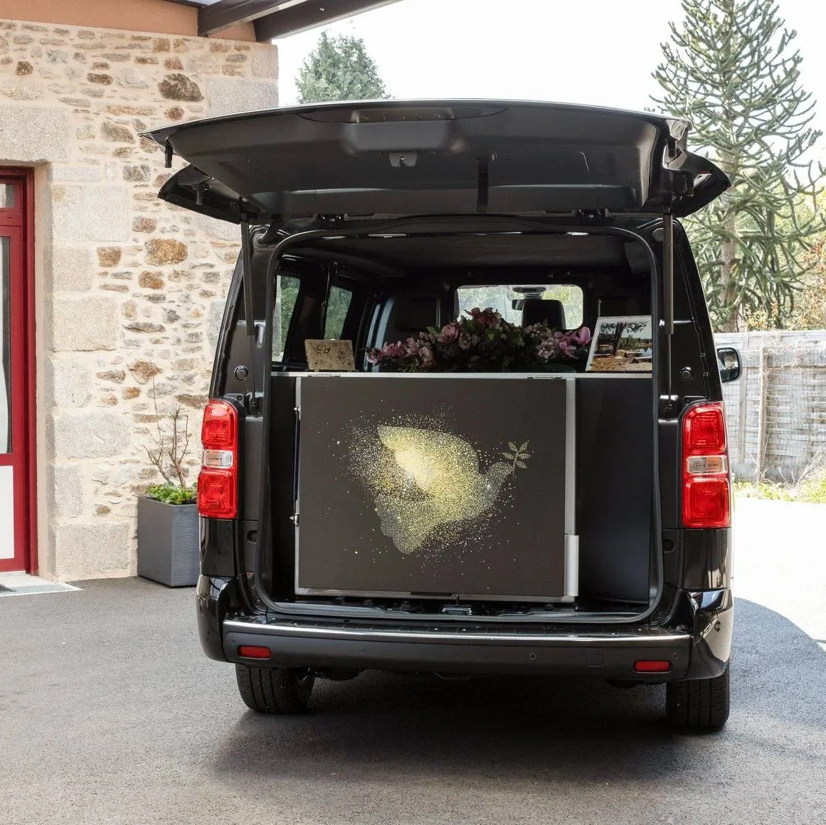 Coffre ouvert d'un corbillard noir révélant un caisson funéraire décoré